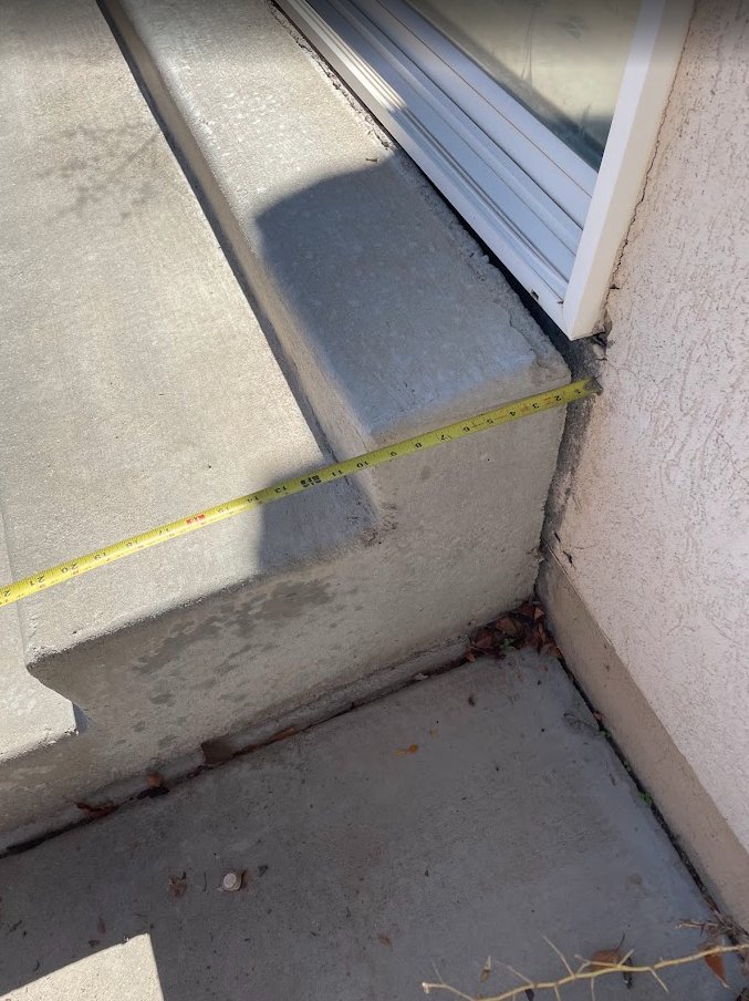 Sunken back patio in Provo before concrete lifting — measuring the settlement gap