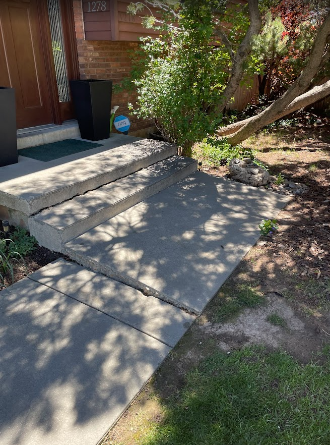 Sunken sidewalk before lifting near utility pedestals